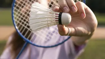 Kobieta trzymająca przed sobą rakietę do badmingtona oraz lotkę