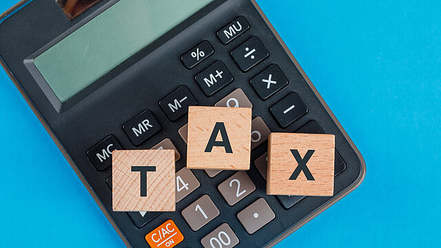 Kalkulator i leżące na nim trzy kostki z literkami T, A, X